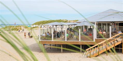 Een sfeervol gedekte tafel op een strandpaviljoen met uitzicht op zee.