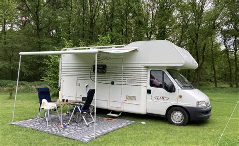 Een ruime camper met alkoof, geparkeerd in een natuurlijke omgeving