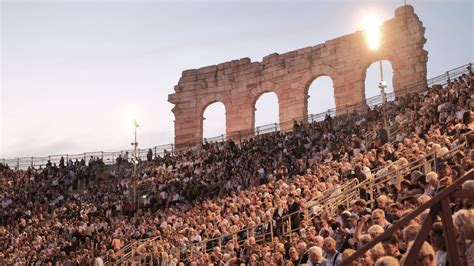 Impressie van het Operafestival in de Arena di Verona met een voorstelling op het podium en publiek op de tribunes.