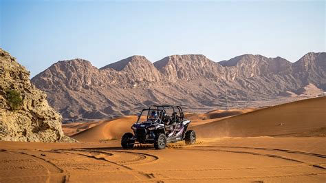 Foto van een dune buggy die door een zanderig, vulkanisch landschap rijdt