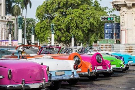 Een groep kleurrijke oldtimers geparkeerd op een plein in Havana.