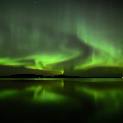 Het Noorderlicht, groen oplichtend boven een besneeuwd IJslands landschap.
