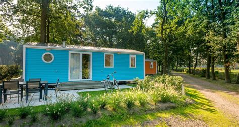 Een luxe stacaravan met veranda en tuinmeubilair op een camping