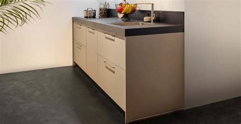 Interieur van een moderne camper met een keukenblok, koelkast, comfortabele zitruimte en een net opgemaakt bed, wat het woongemak illustreert.