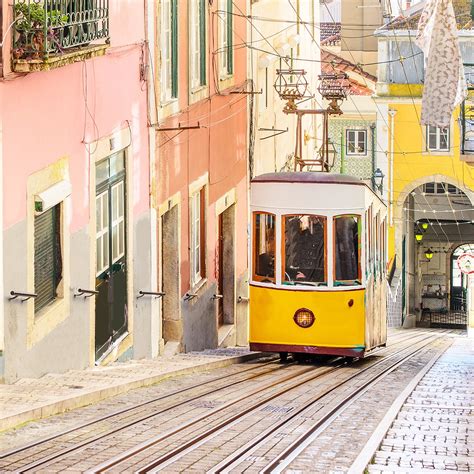 Gele tram 28 die door een smalle straat in Lissabon rijdt