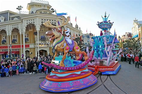 Familie geniet van een parade in Disneyland Parijs met kleurrijke praalwagens en personages.