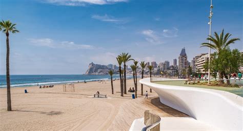 Een panoramafoto van het Levante-strand in Benidorm met de boulevard en de bebouwing op de achtergrond.