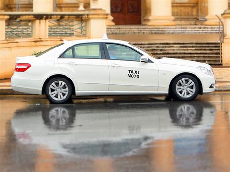 Een witte taxi op Malta in een straat met traditionele Maltese architectuur.