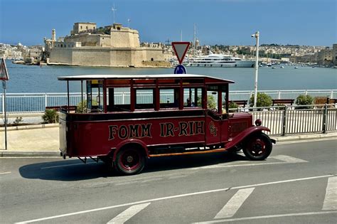 Een moderne Maltese bus bij een bushalte in een typisch Maltees stadje.