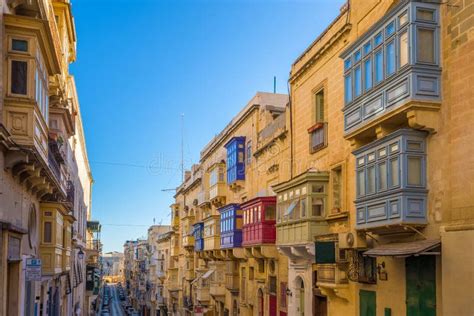 Een compacte huurauto geparkeerd op een smalle straat in Malta met traditionele gebouwen op de achtergrond.