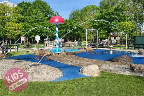 Kinderen spelen in een waterspeeltuin met sproeiers en kleine glijbanen