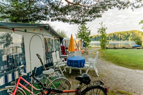 Een zonnige foto van Strandcamping Anderwald aan de Faakersee, met kampeerders die genieten van het meer.