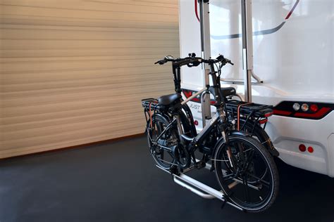 Illustratie van een camper met een fietsendrager en luifel, klaar voor vertrek.