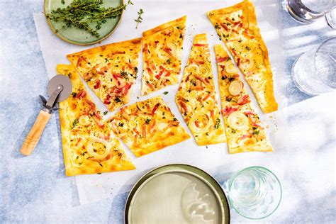 Gezellige tafel met Elzasser specialiteiten, zoals Flammkuchen en een glas witte wijn