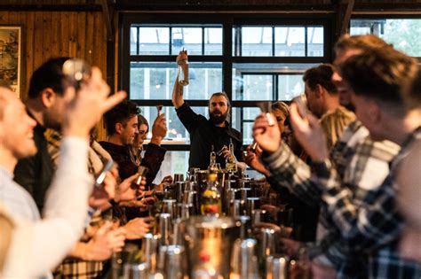 Groep mensen die enthousiast deelnemen aan een cocktailworkshop in Leiden, met barmannen die demonstraties geven.