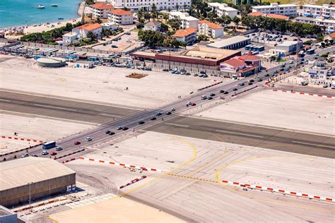 Schematische weergave van de ligging van Gibraltar Airport op het schiereiland, met de landingsbaan die deels over zee loopt en de weg die de baan kruist.