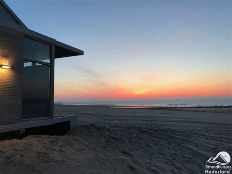 Een sfeervolle foto van een strandhuisje bij zonsondergang met uitzicht op zee.