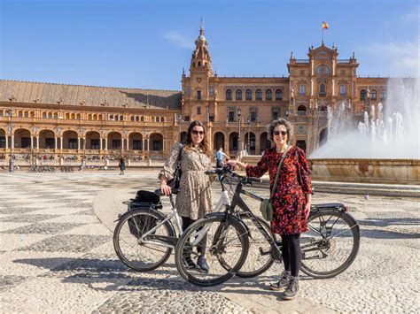 Stadsgezicht van Sevilla met fietsers op een promenade langs de rivier