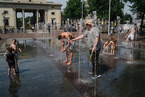 Kinderen die verkoeling zoeken bij een watersproeier in Slagharen op een hete dag.