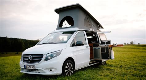 Een groep vrienden die lachend instapt bij een gehuurde Mercedes Vito camper.