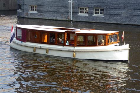 Een klassieke salonboot vaart door een weids Fries landschap met water en groen.